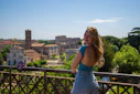 A woman standing on a bridge with a city in the background