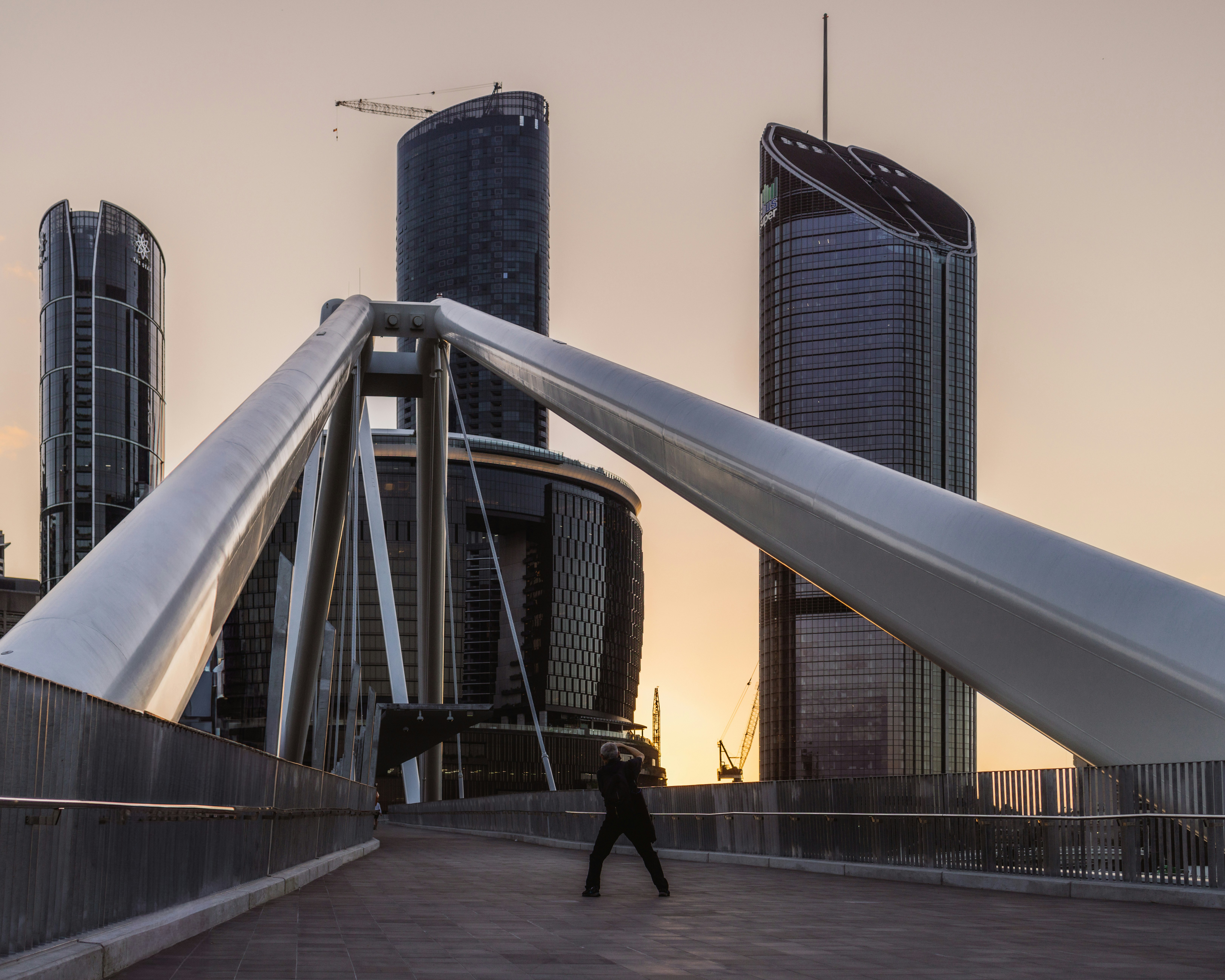 A man walking across a bridge in front of tall buildings