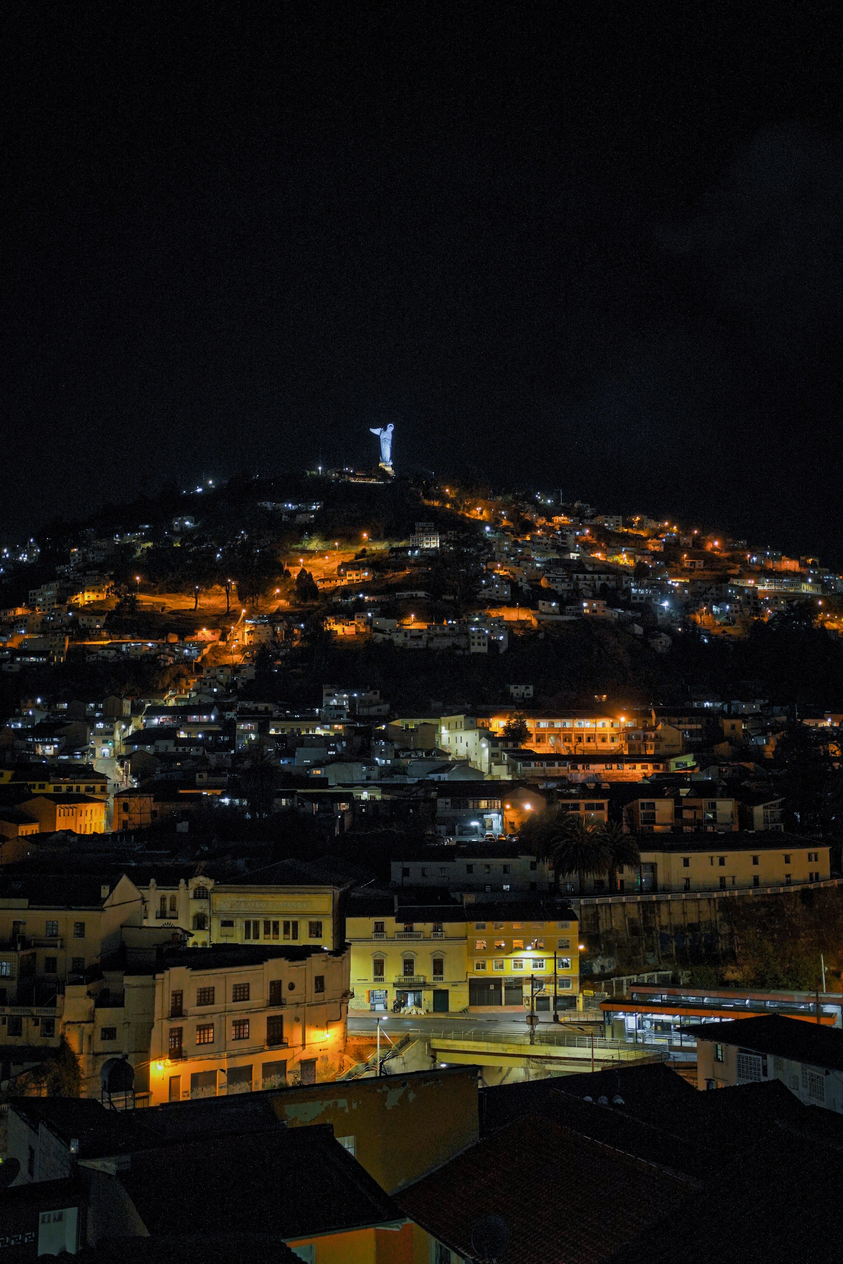 Quito illuminated at night with El Panecillo rising beyond