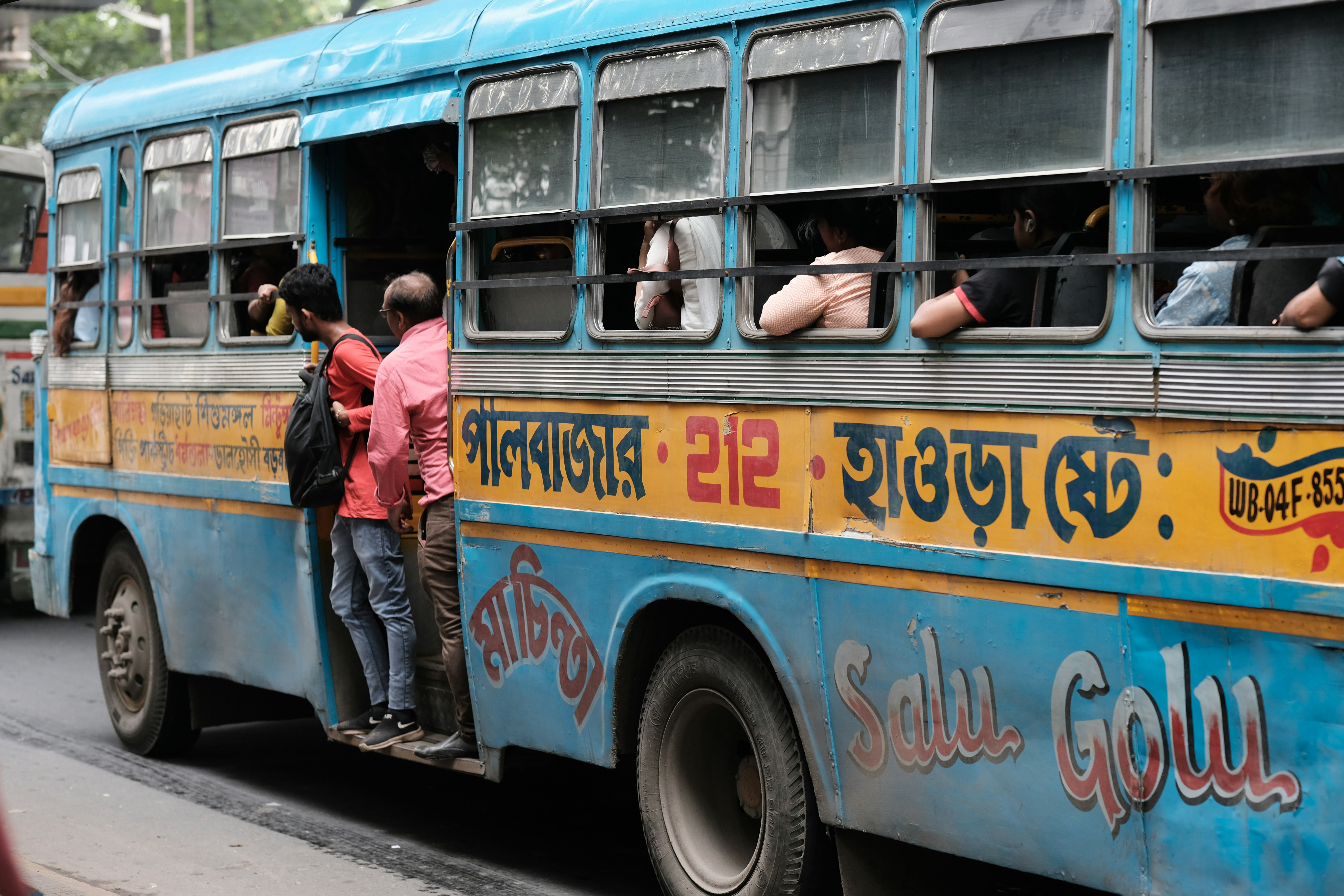 A group of people standing on the side of a bus