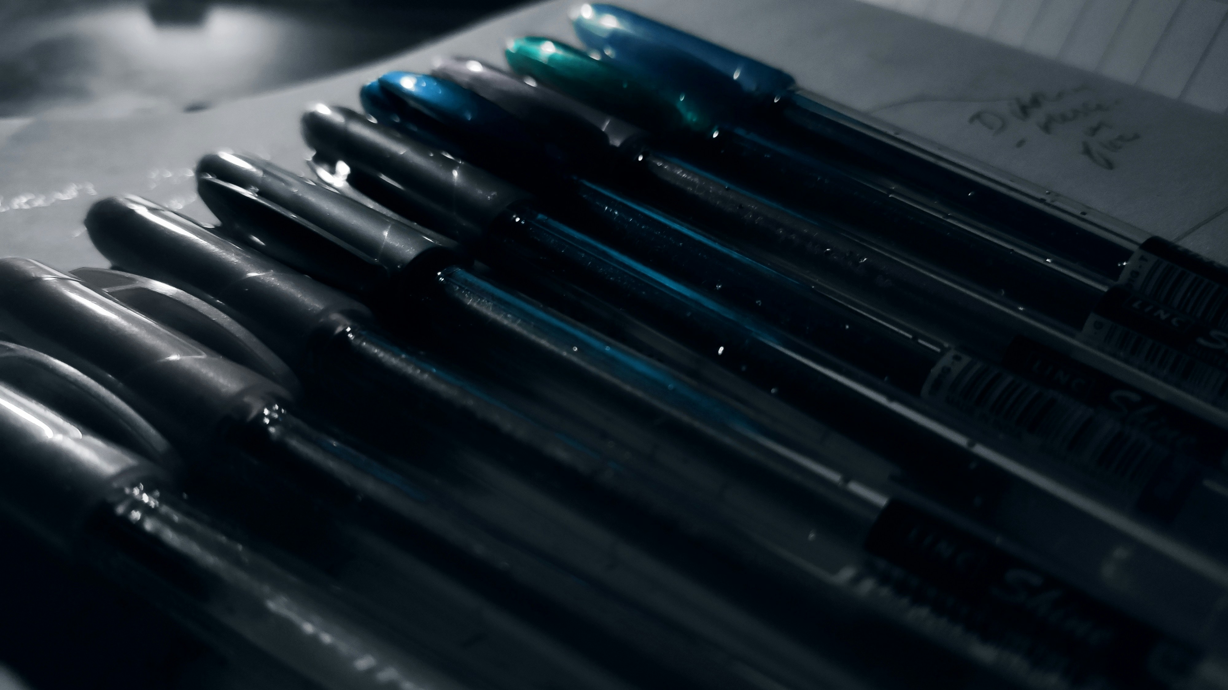 Set of blue and black ballpoint pens arranged neatly on white surface