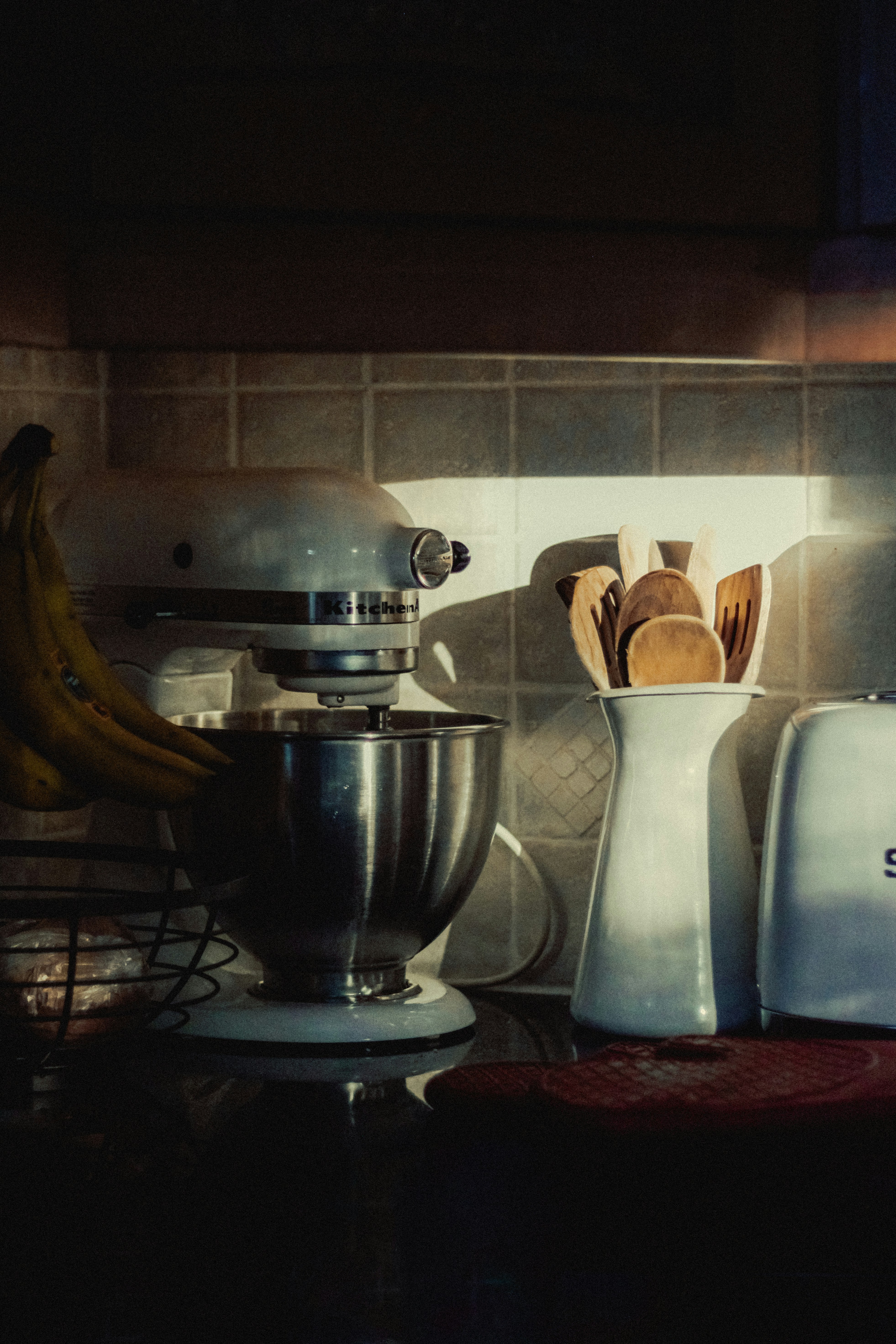 A kitchen counter with a blender, bananas, and other kitchen items