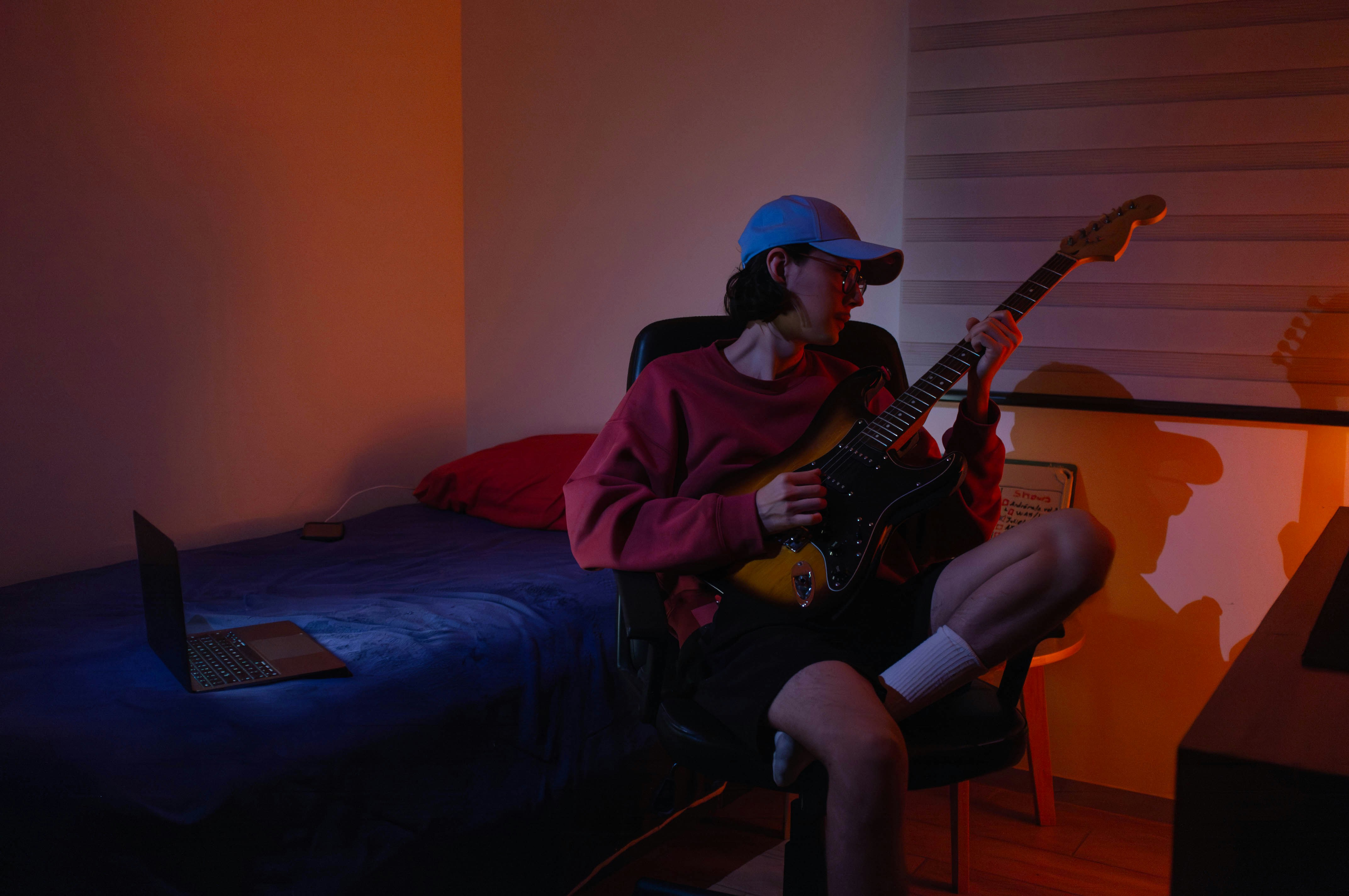 A man sitting in a chair playing a guitar photo – Free Music Image on ...