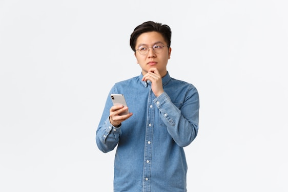 A man in a blue shirt is holding a cell phone