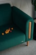 A green chair with oranges on the floor