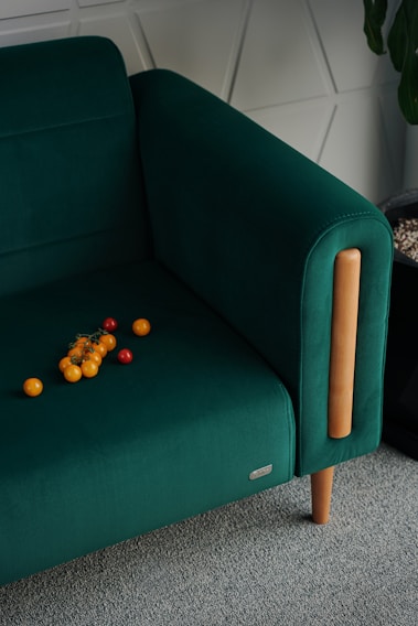 A green chair with oranges on the floor