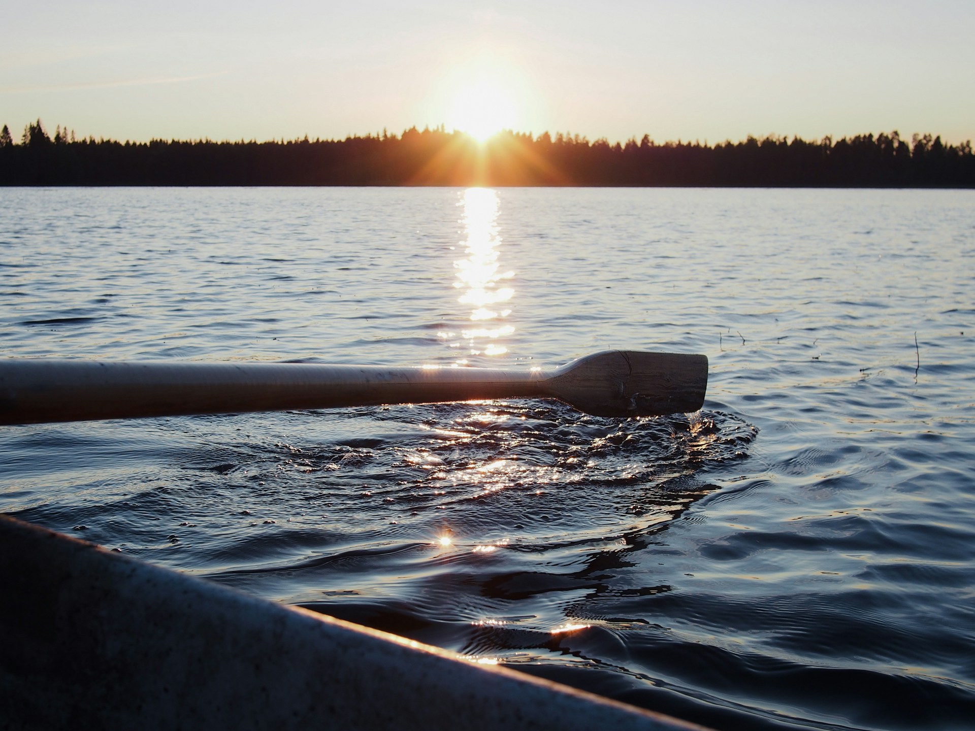 The sun is setting over the water on a boat