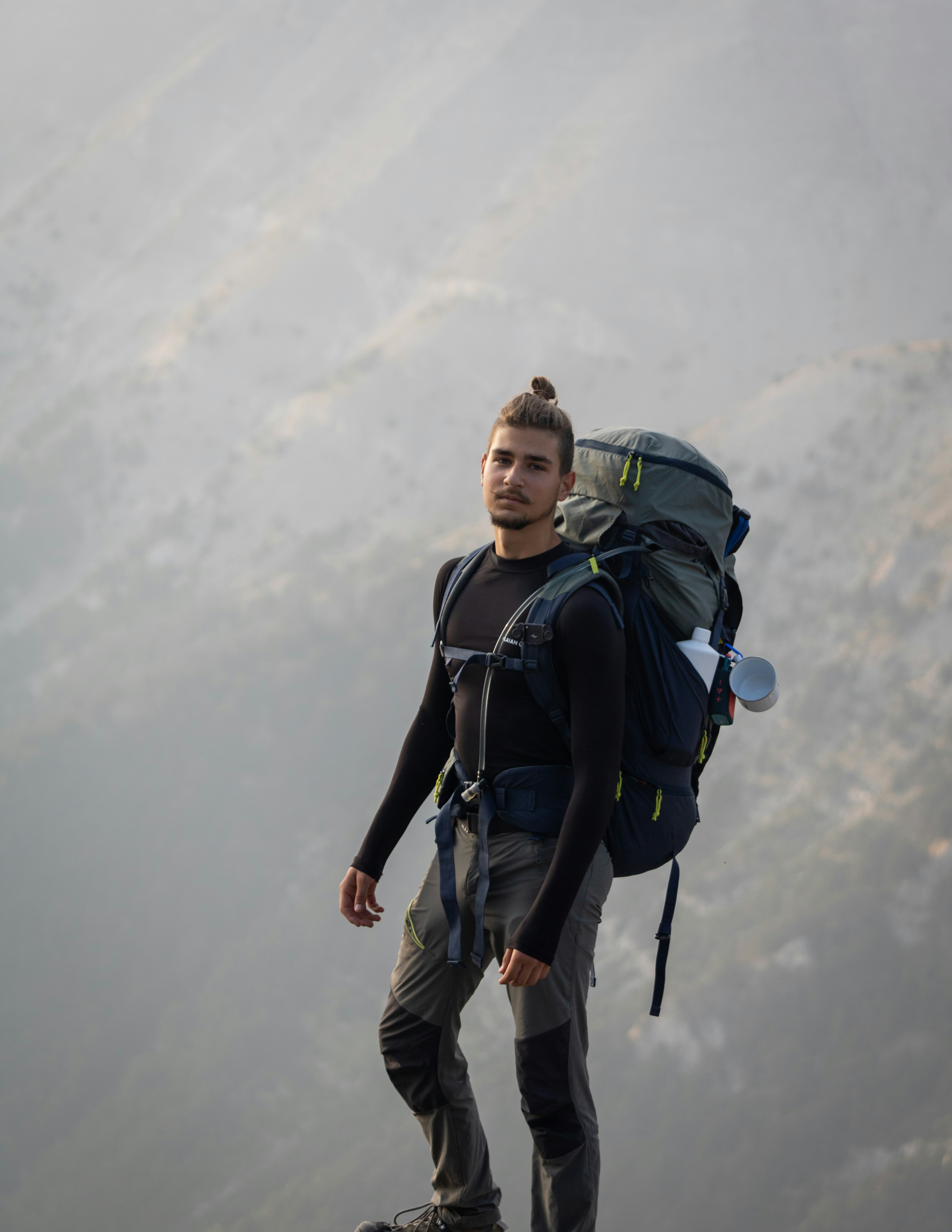 A man standing on top of a mountain with a backpack photo – Free Man ...