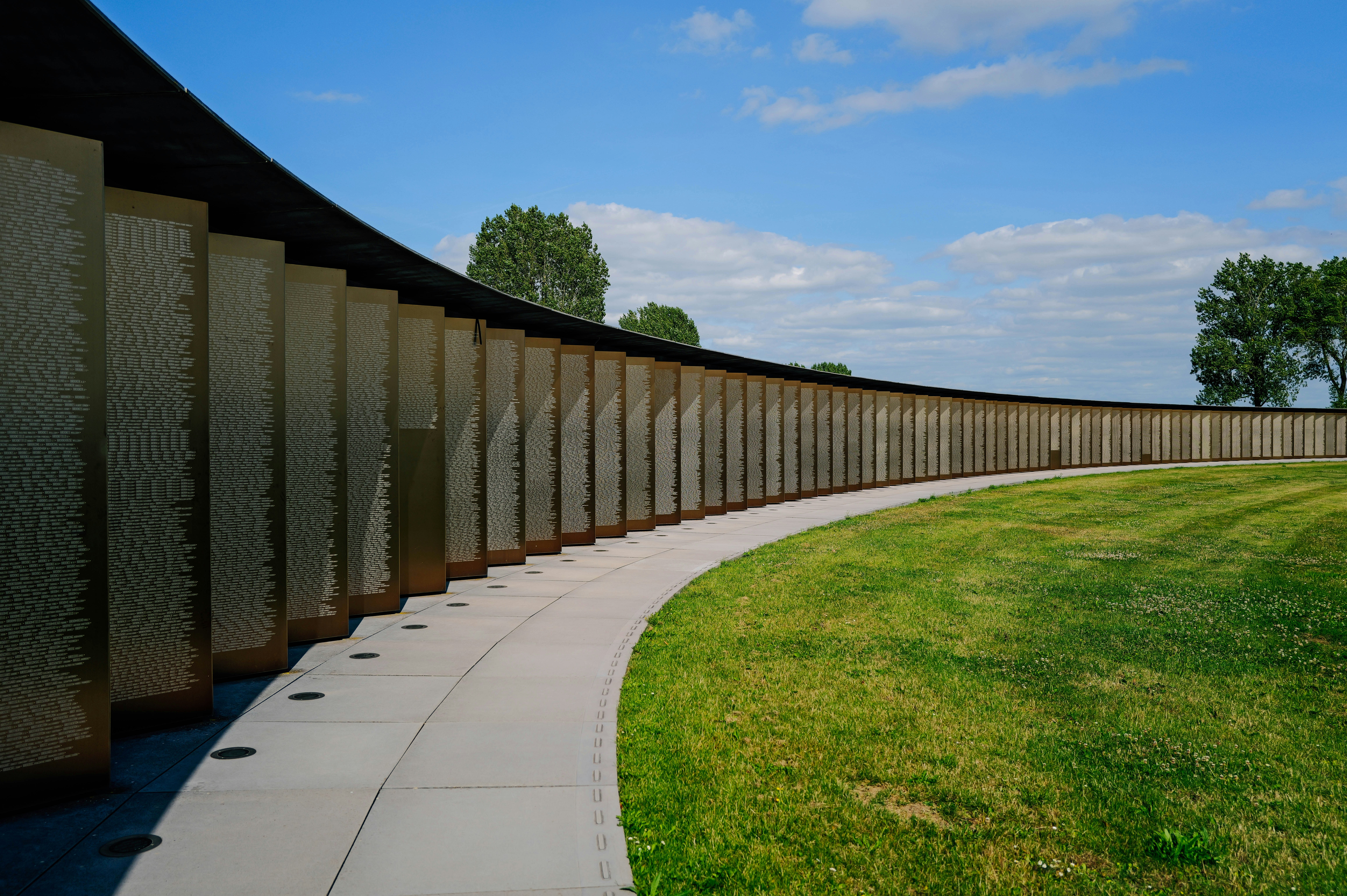 A long curved walkway next to a grassy field