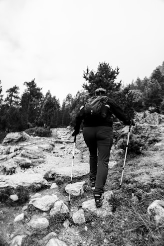 A person walking up a rocky hill with ski poles