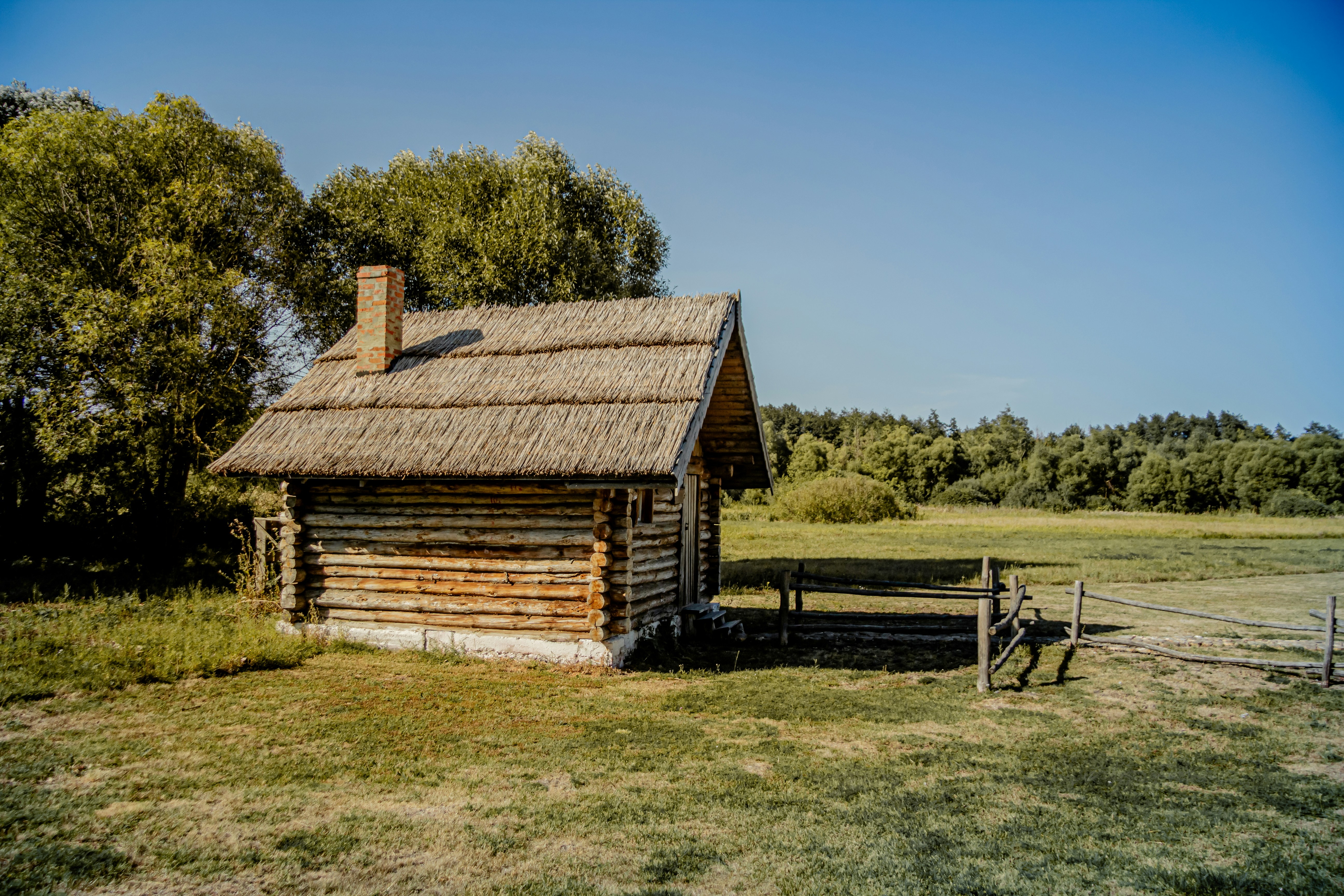 An old log cabin in the middle of a field