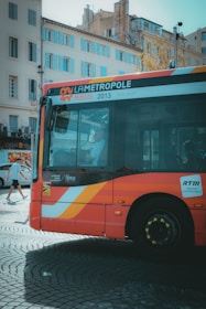 A red bus is parked on a cobblestone street