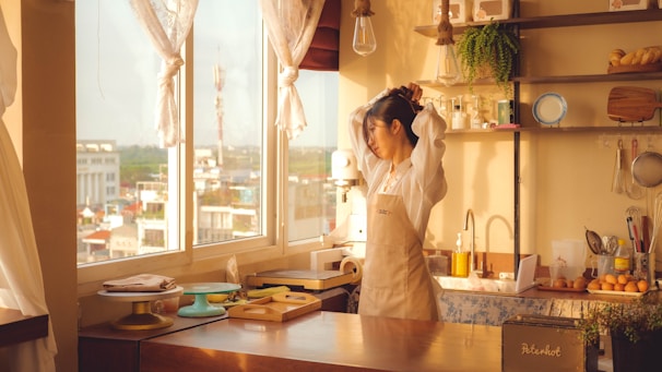 A woman standing in a kitchen next to a window