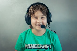 A young boy wearing headphones and a green shirt
