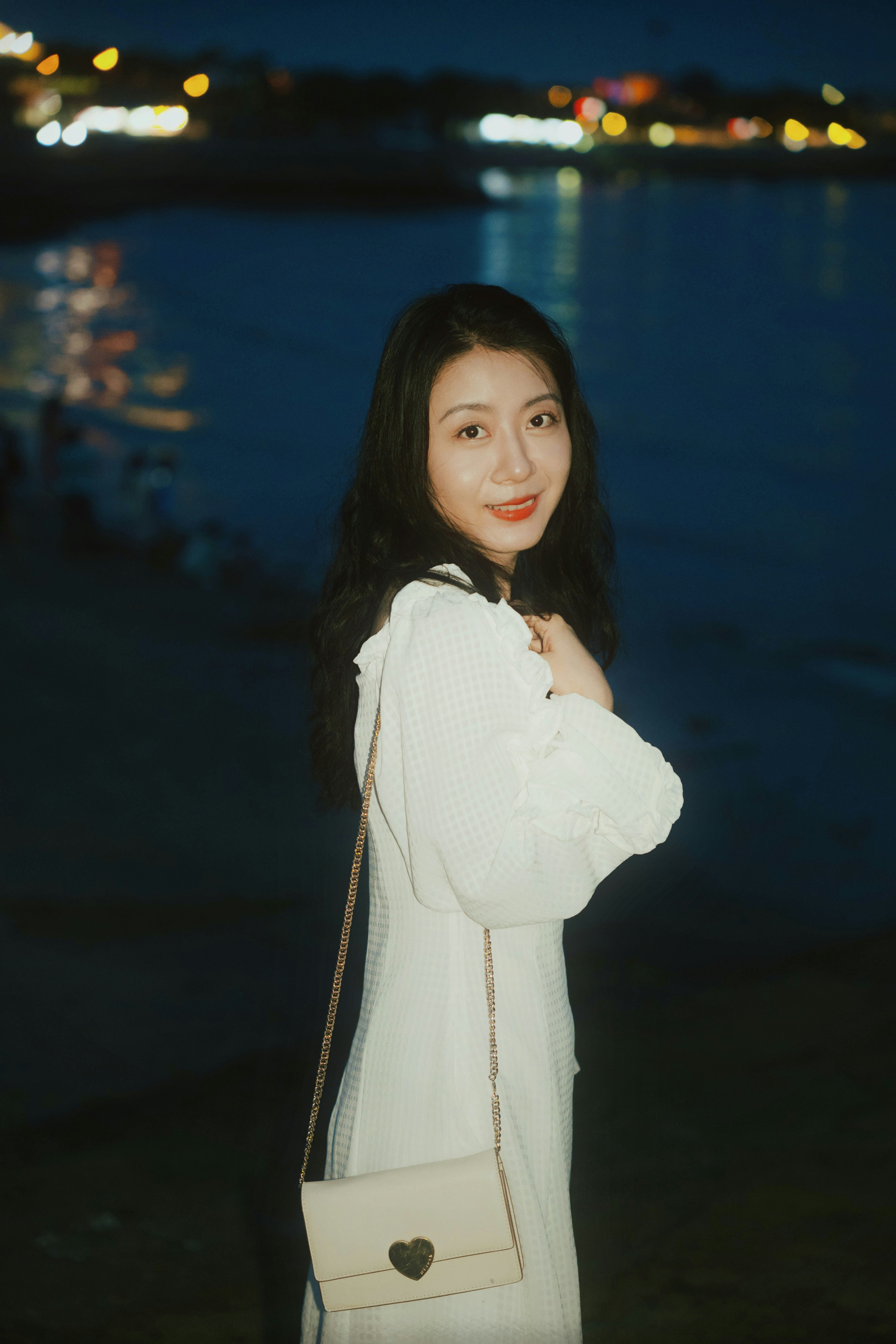 A woman standing next to a body of water at night