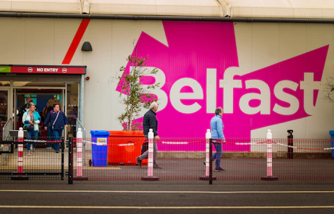 People are walking past a store with a pink sign