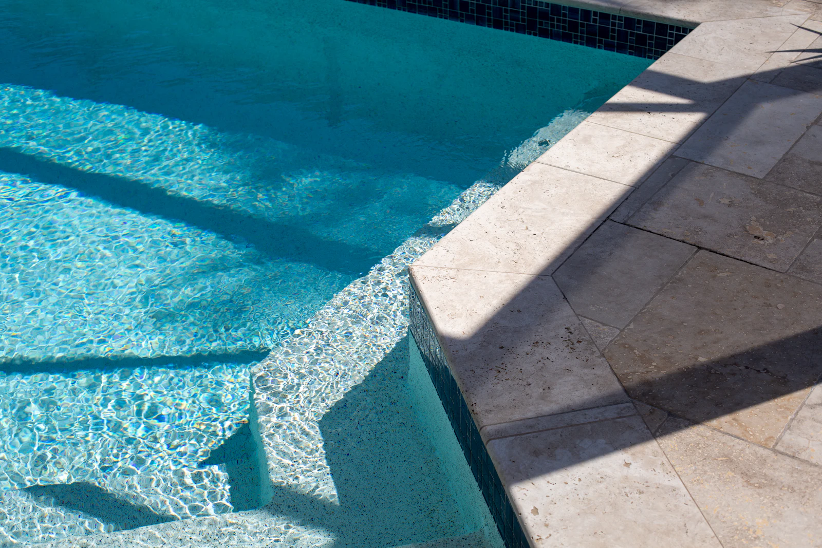 Stone coping and pavers meeting the pool's waterline tile