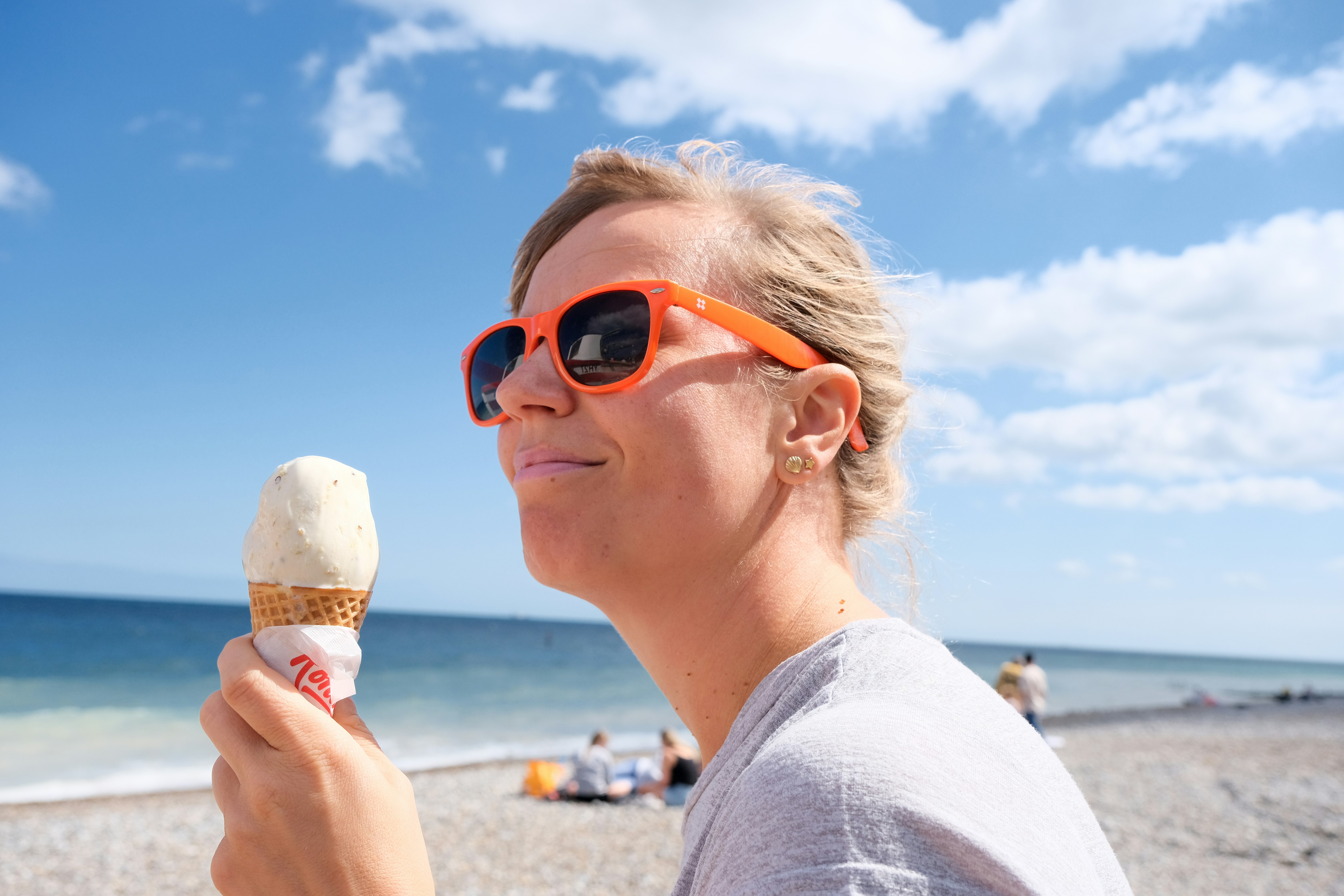 A woman eating an ice cream cone on the beach