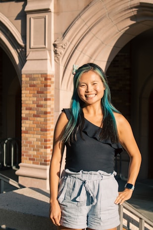 A woman with blue hair standing in front of a building