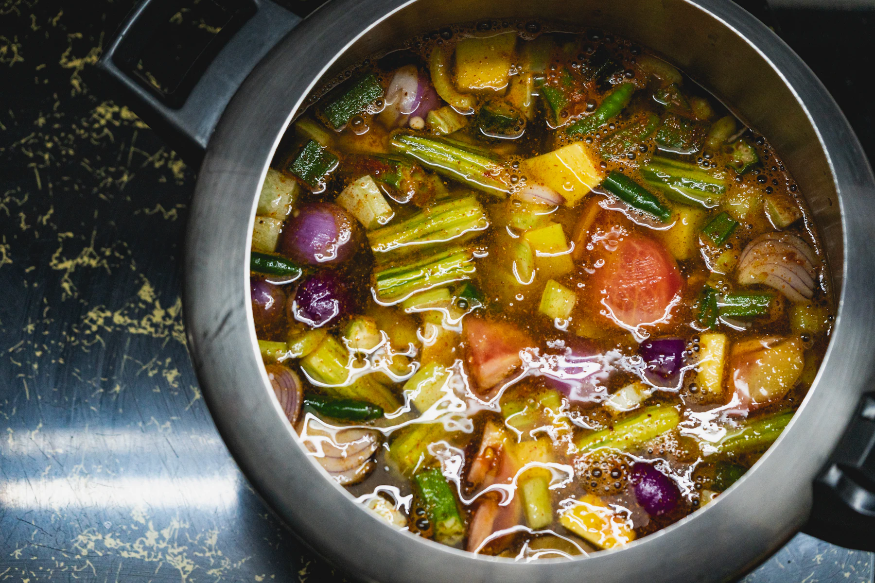 A large pot of vegetable soup simmering on a stovetop