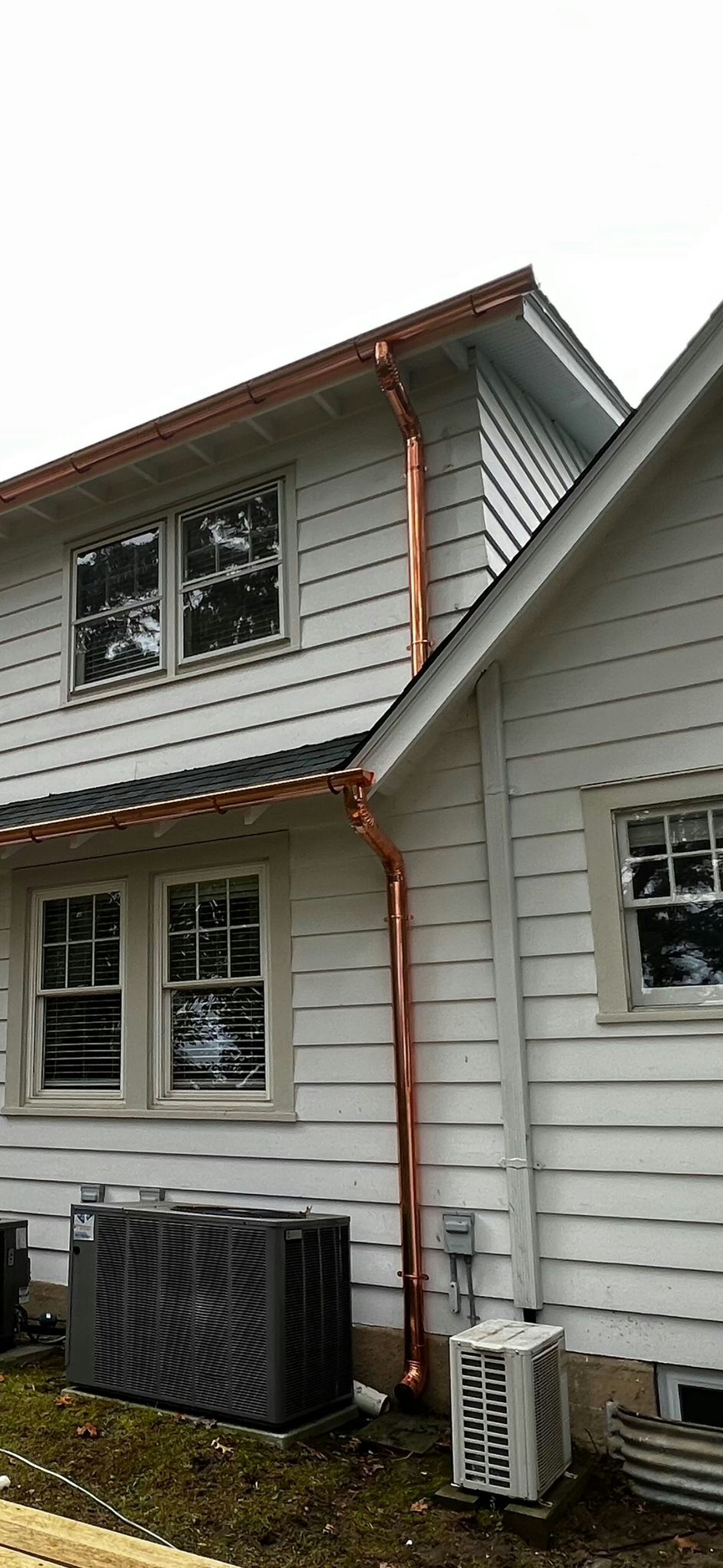 Copper half-round gutter on heritage home, warm afternoon light, aged brick facade