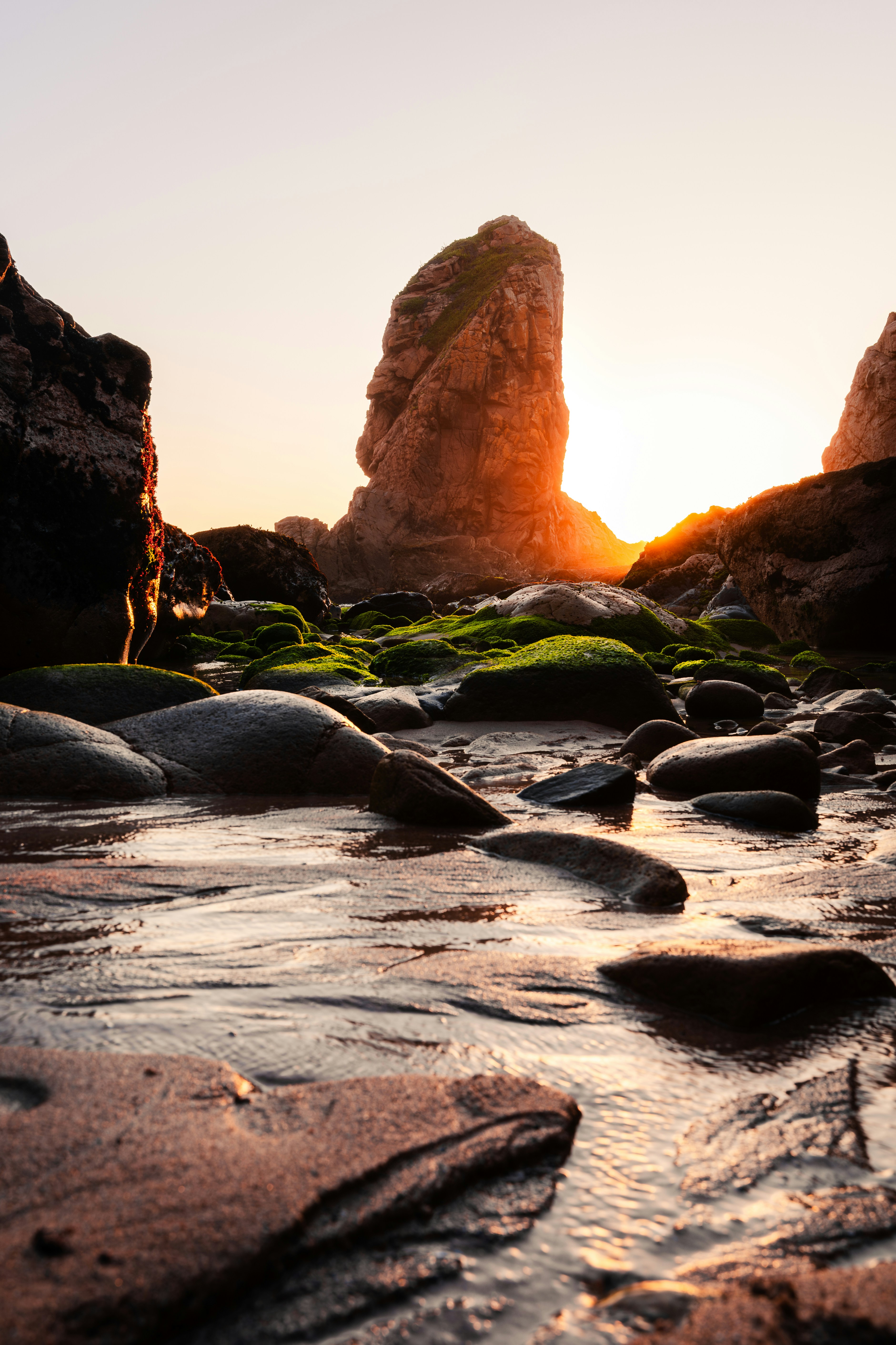 Die Sonne geht über den Felsen am Strand unter