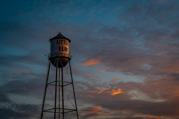 A water tower in the middle of a sunset