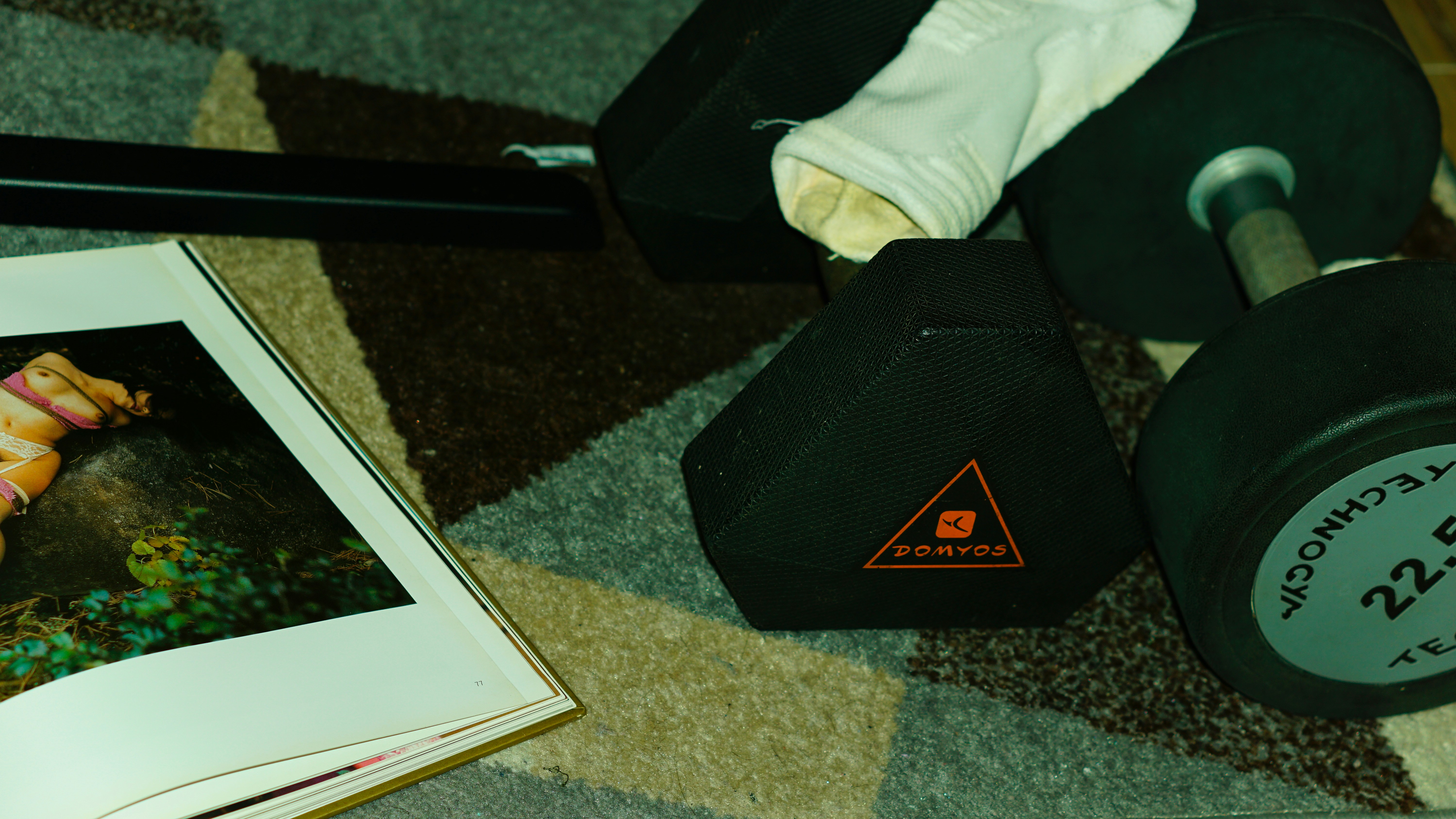 A teddy bear sitting on the floor next to a book