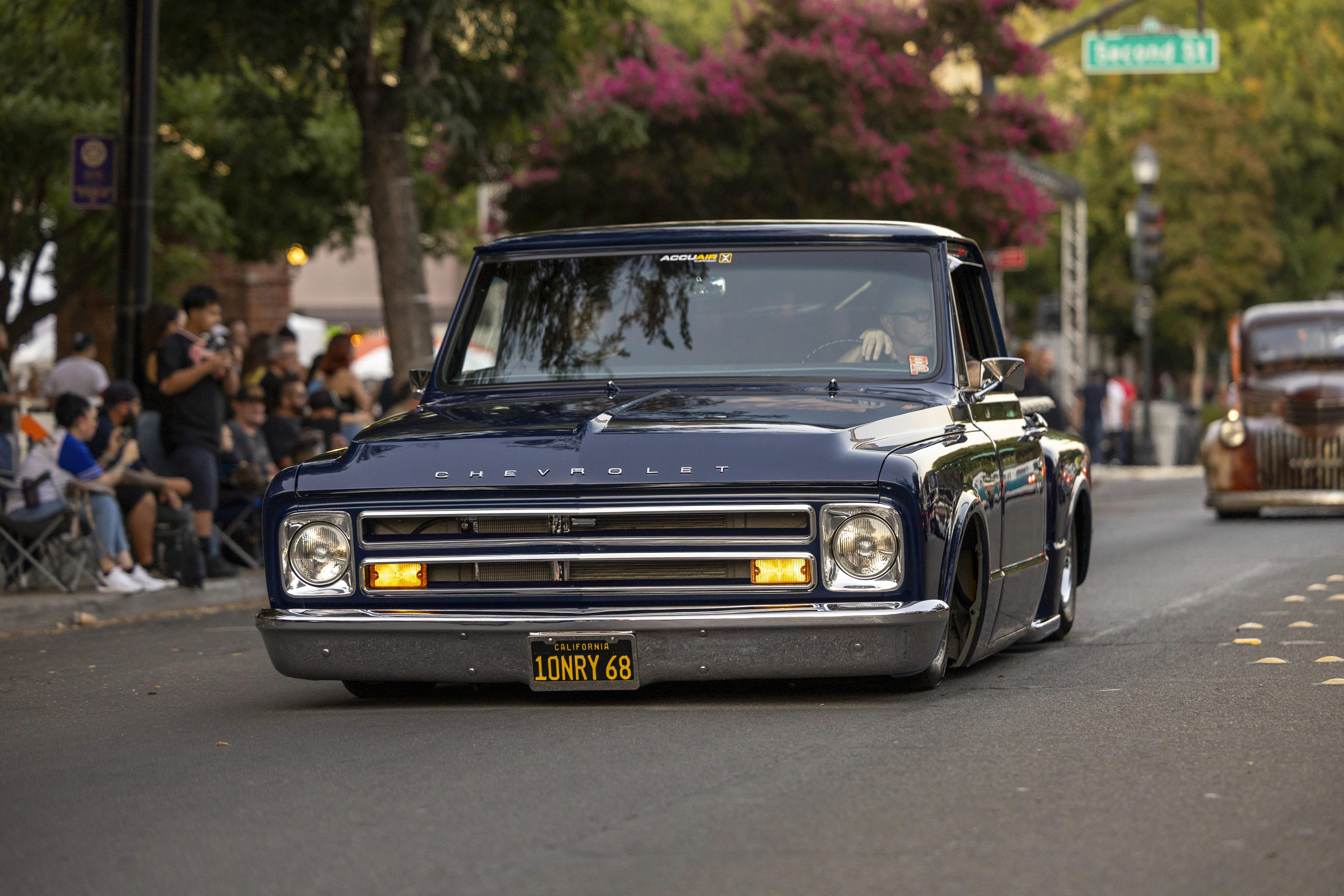 A truck driving down a street next to a crowd of people