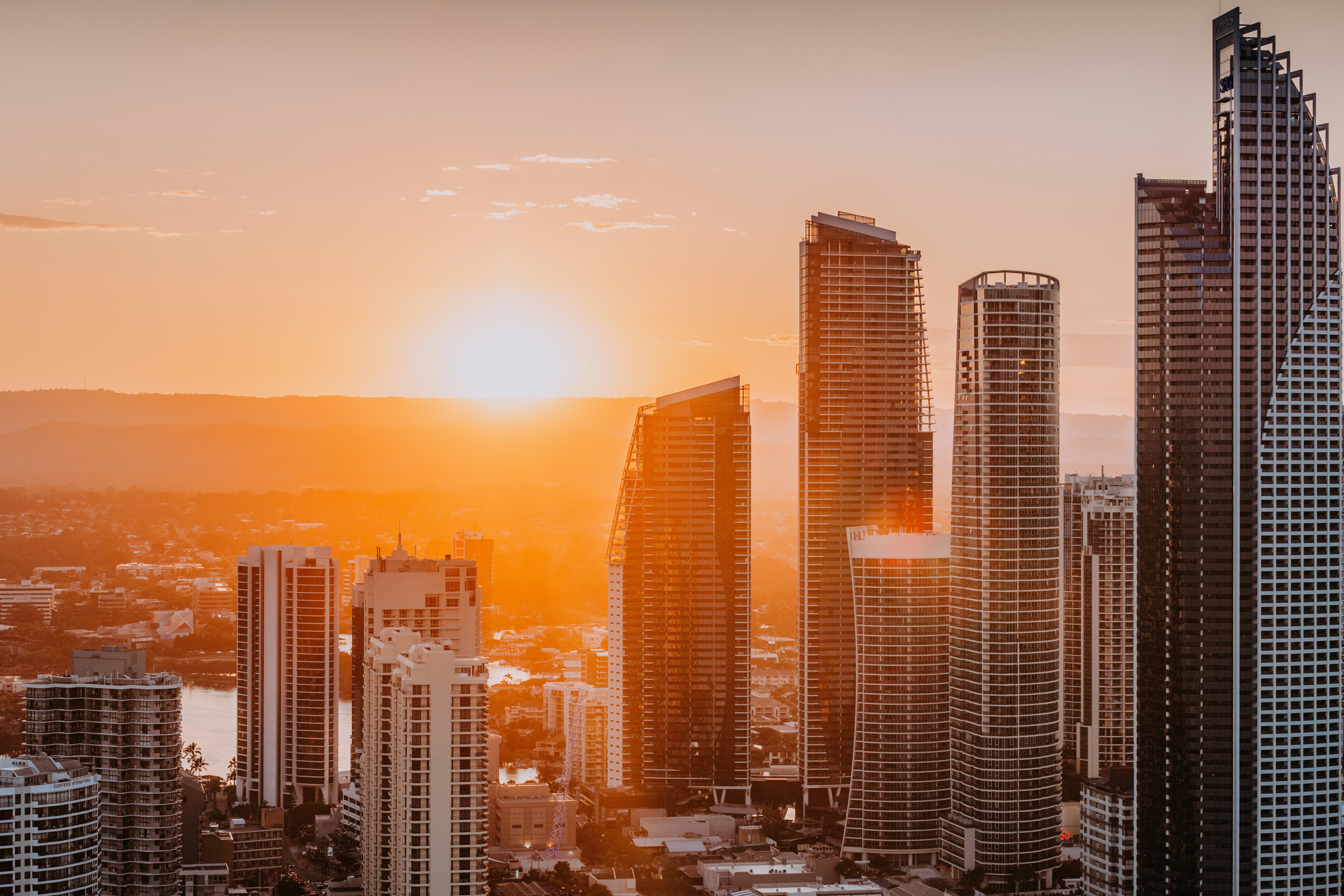 The sun is setting over a city with tall buildings