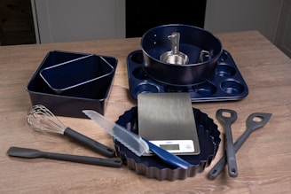 A wooden table topped with a pan, spatula and other kitchen utensils
