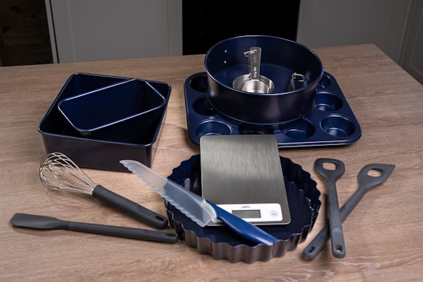 A wooden table topped with a pan, spatula and other kitchen utensils