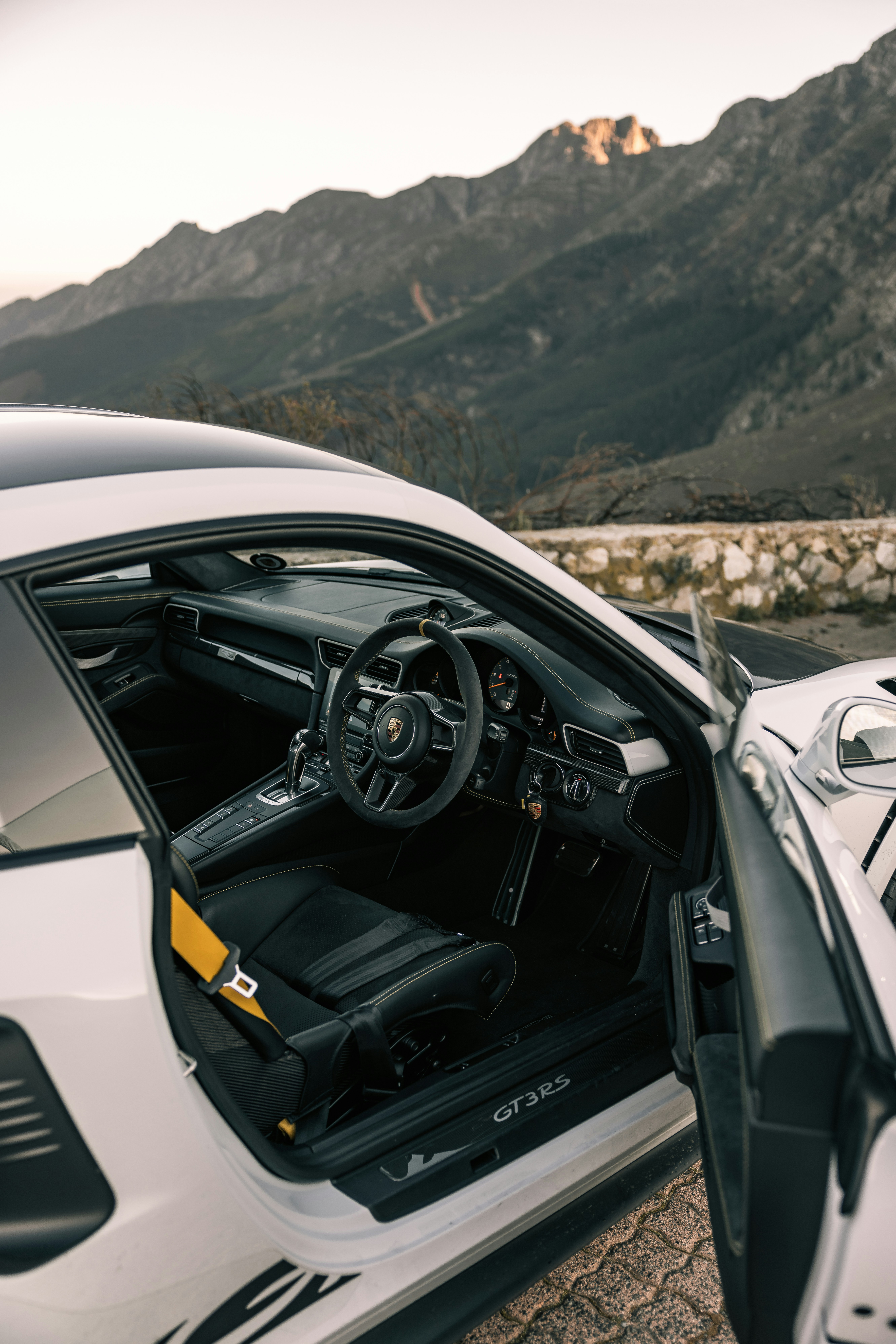 The interior of a white sports car with mountains in the background