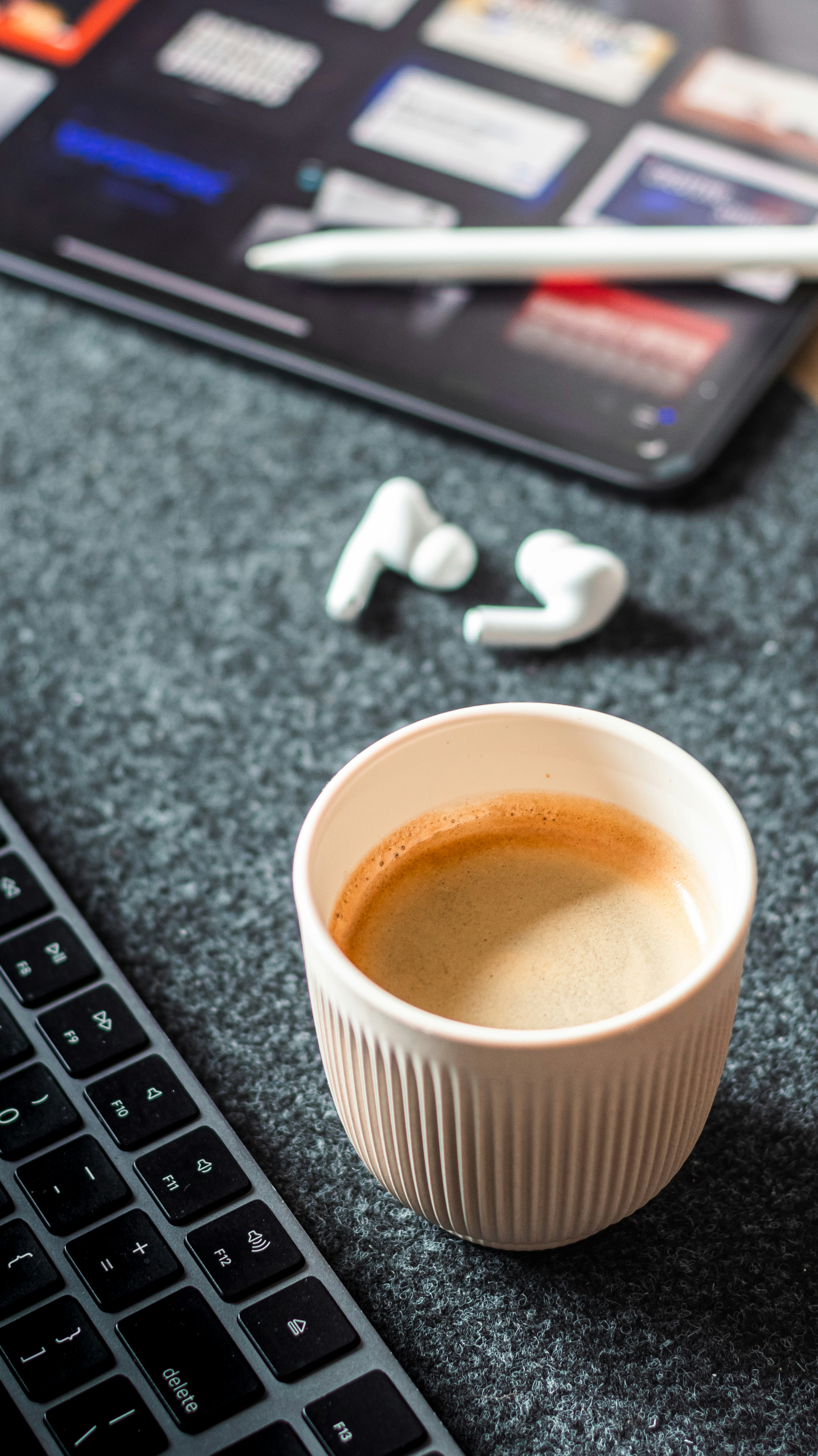Coffee cup and keyboard on a felt desk mat.
