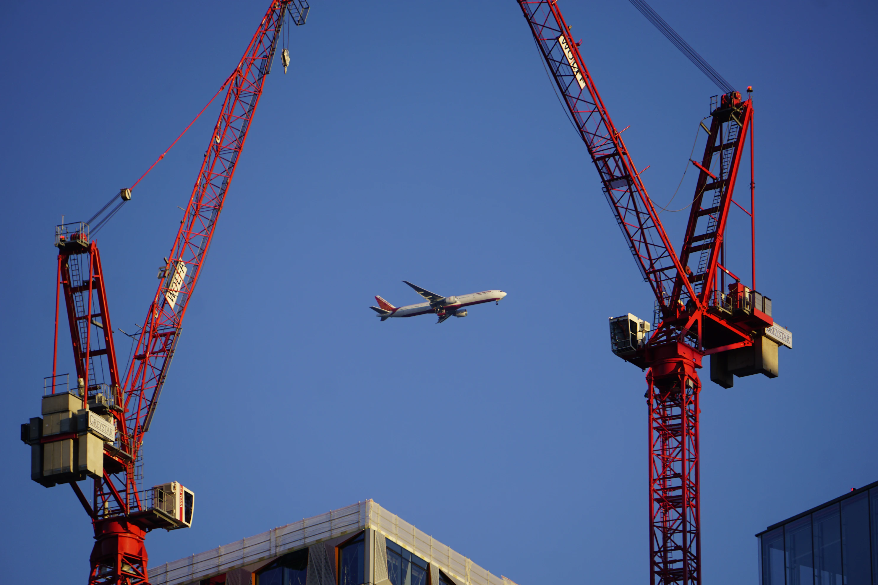 A plane flying over a building under a blue sky.