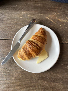 A croissant on a plate with butter and a knife