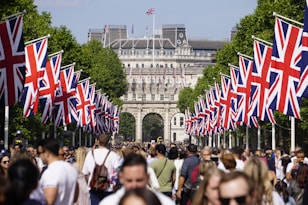 A crowd of people walking down a street with flags