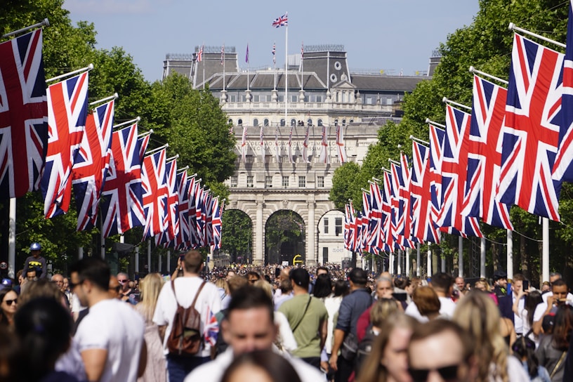 A crowd of people walking down a street with flags