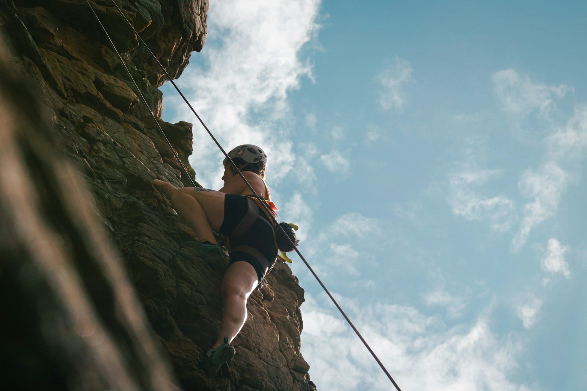 A woman climbing up the side of a cliff