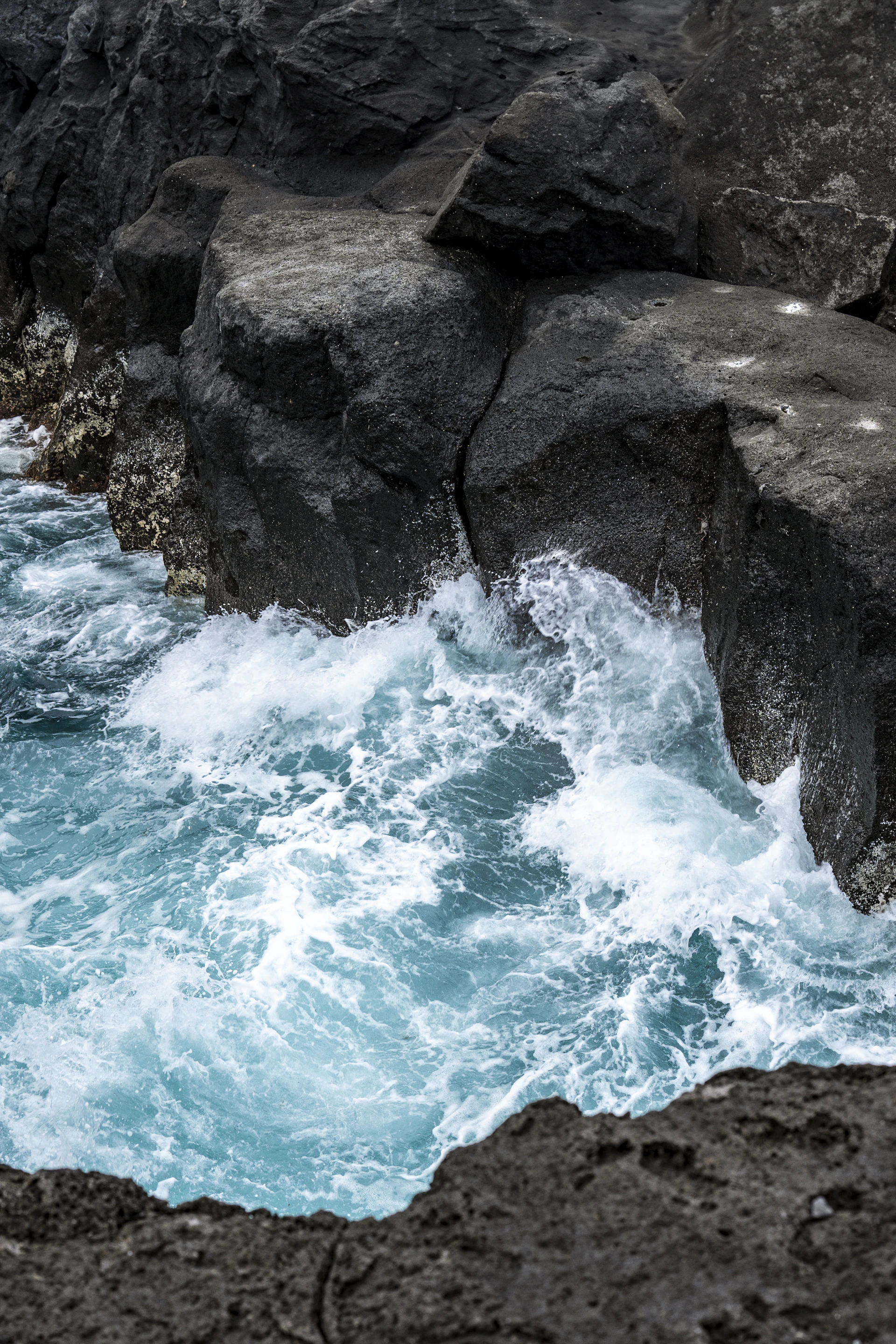 A man standing on top of a cliff next to a body of water