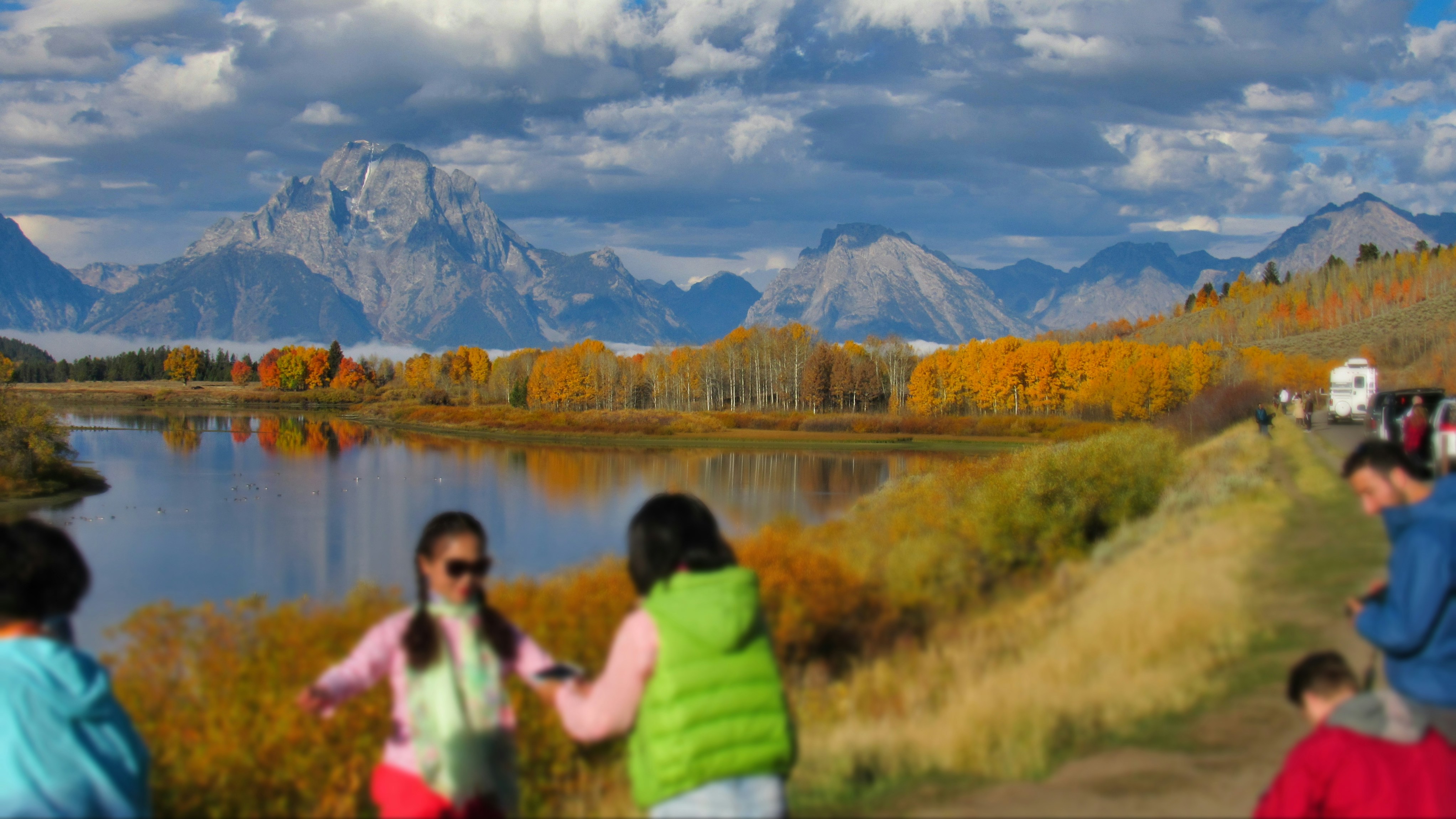 A group of people walking down a path next to a lake
