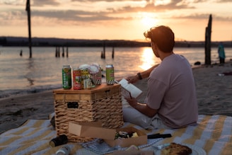A man sitting on a beach next to a basket of food