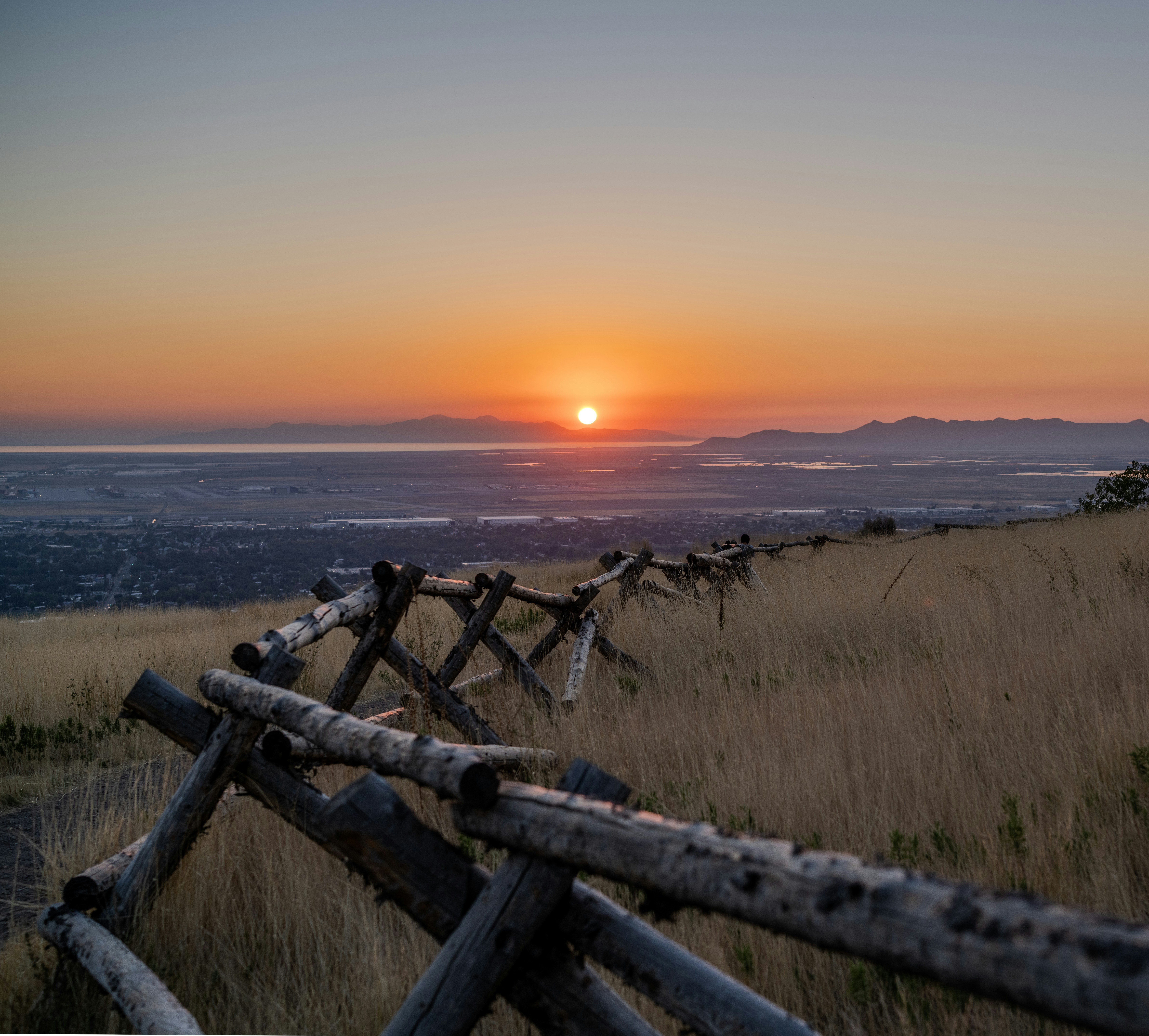 The sun is setting behind a wooden fence