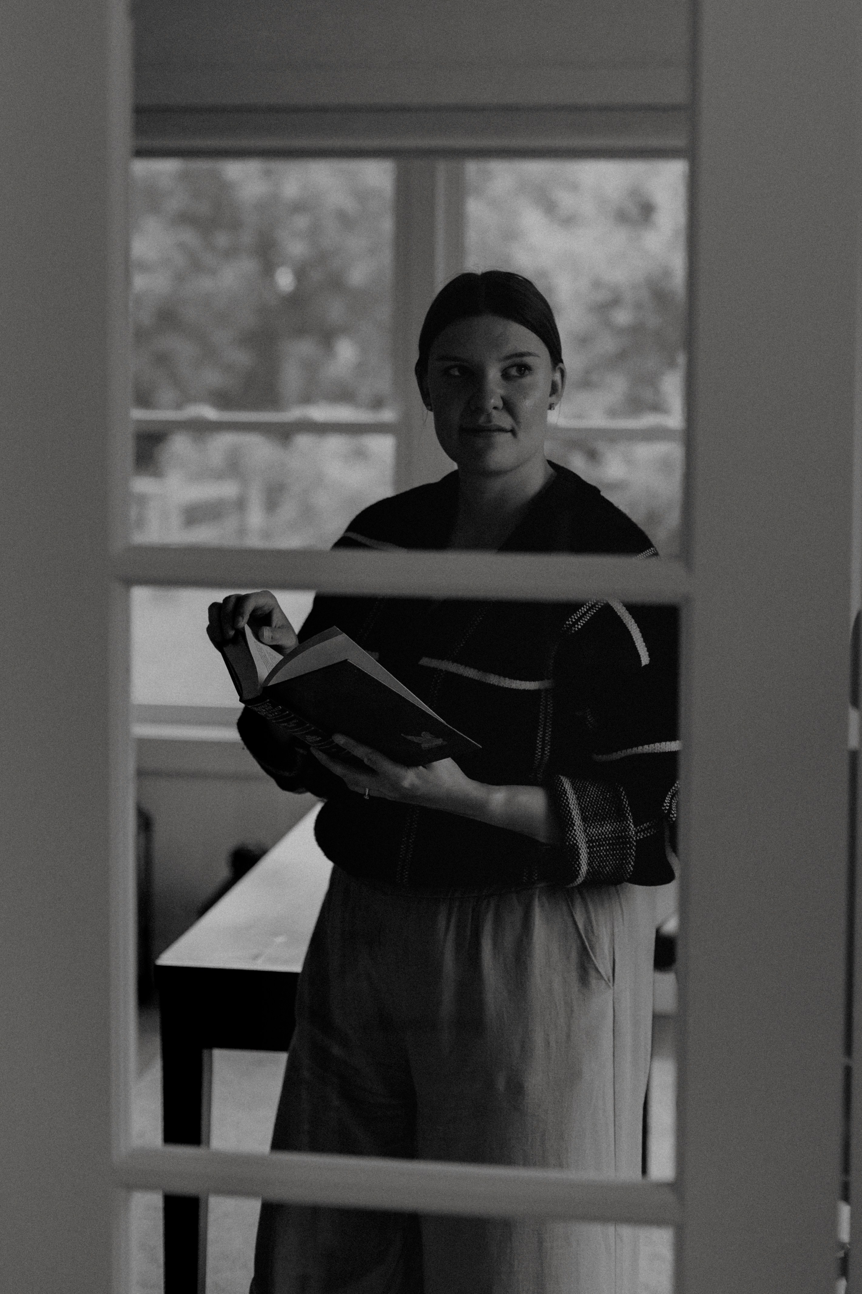 A woman standing in front of a door holding a book