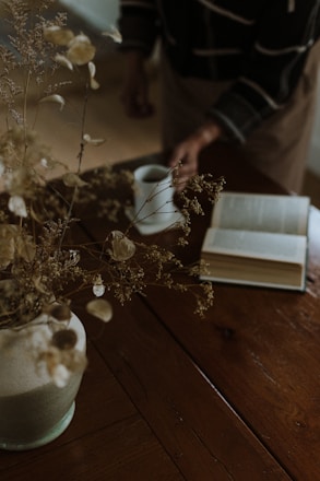 A vase with flowers and a book on a table