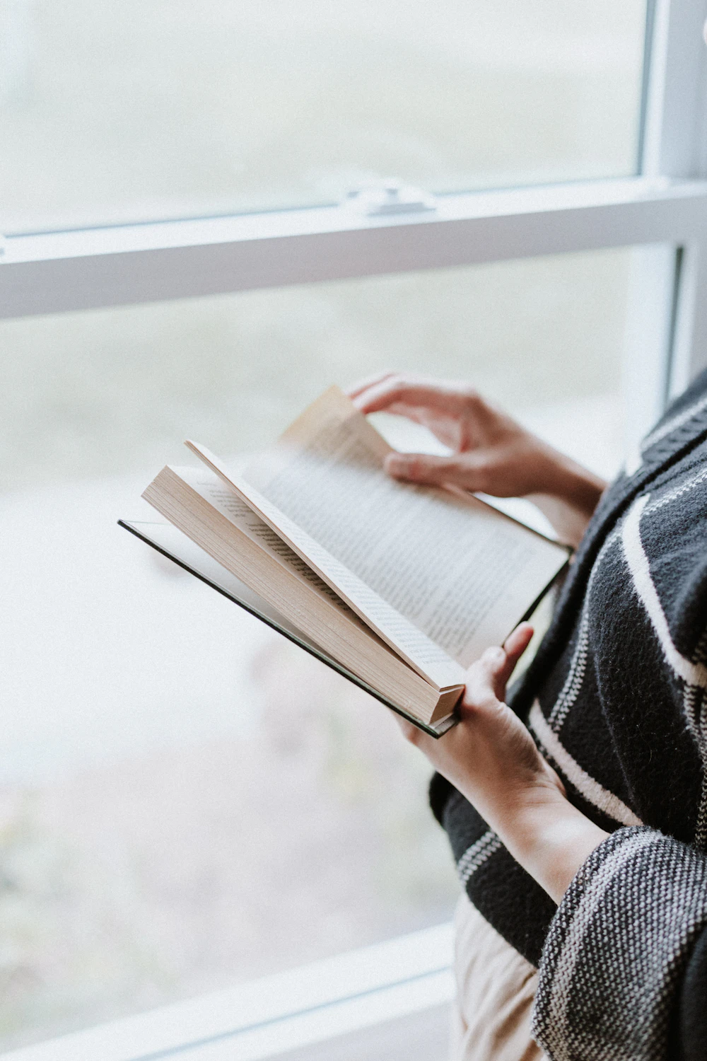 A woman reading by a window in soft morning light