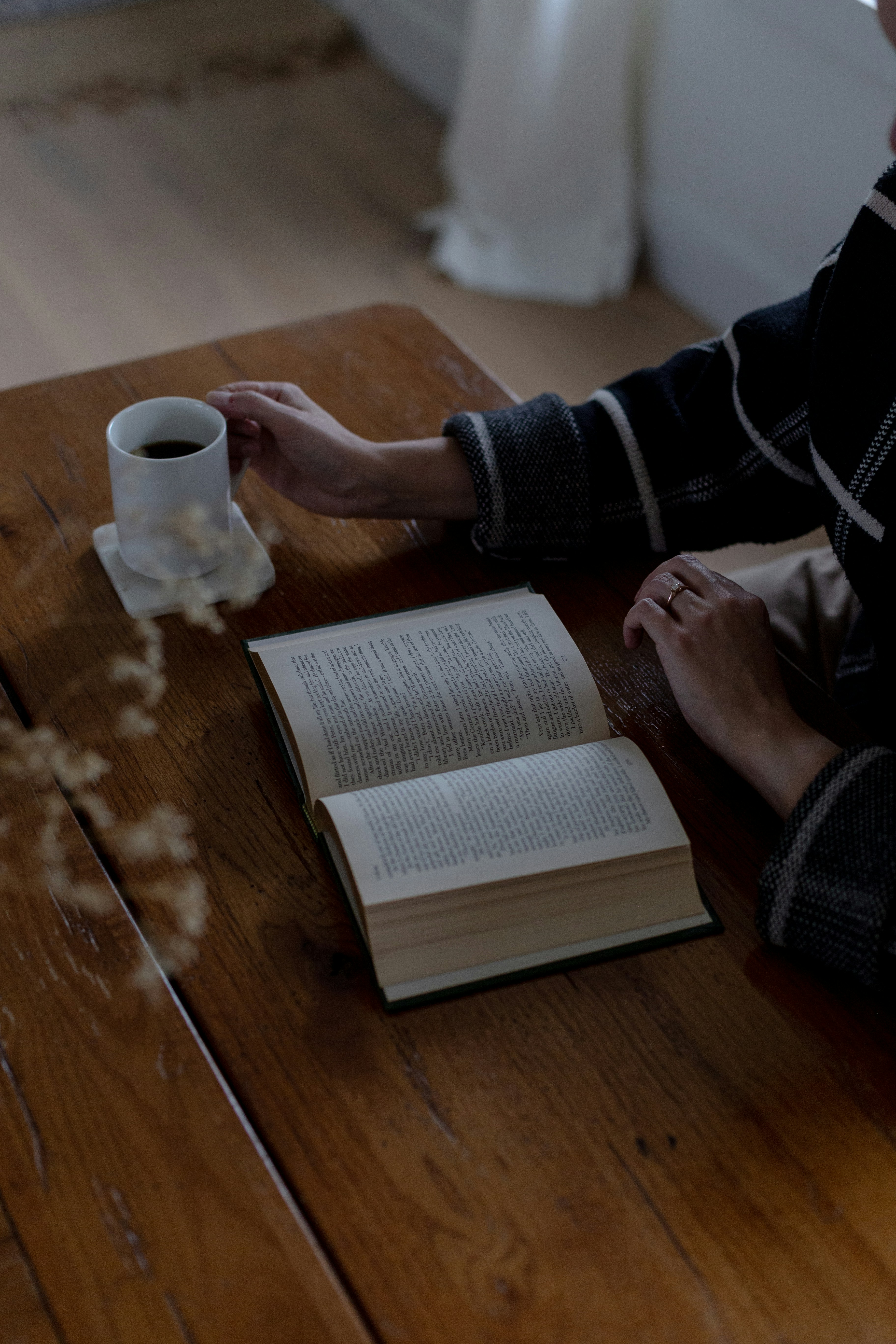 A person sitting at a table with a book and a cup of coffee