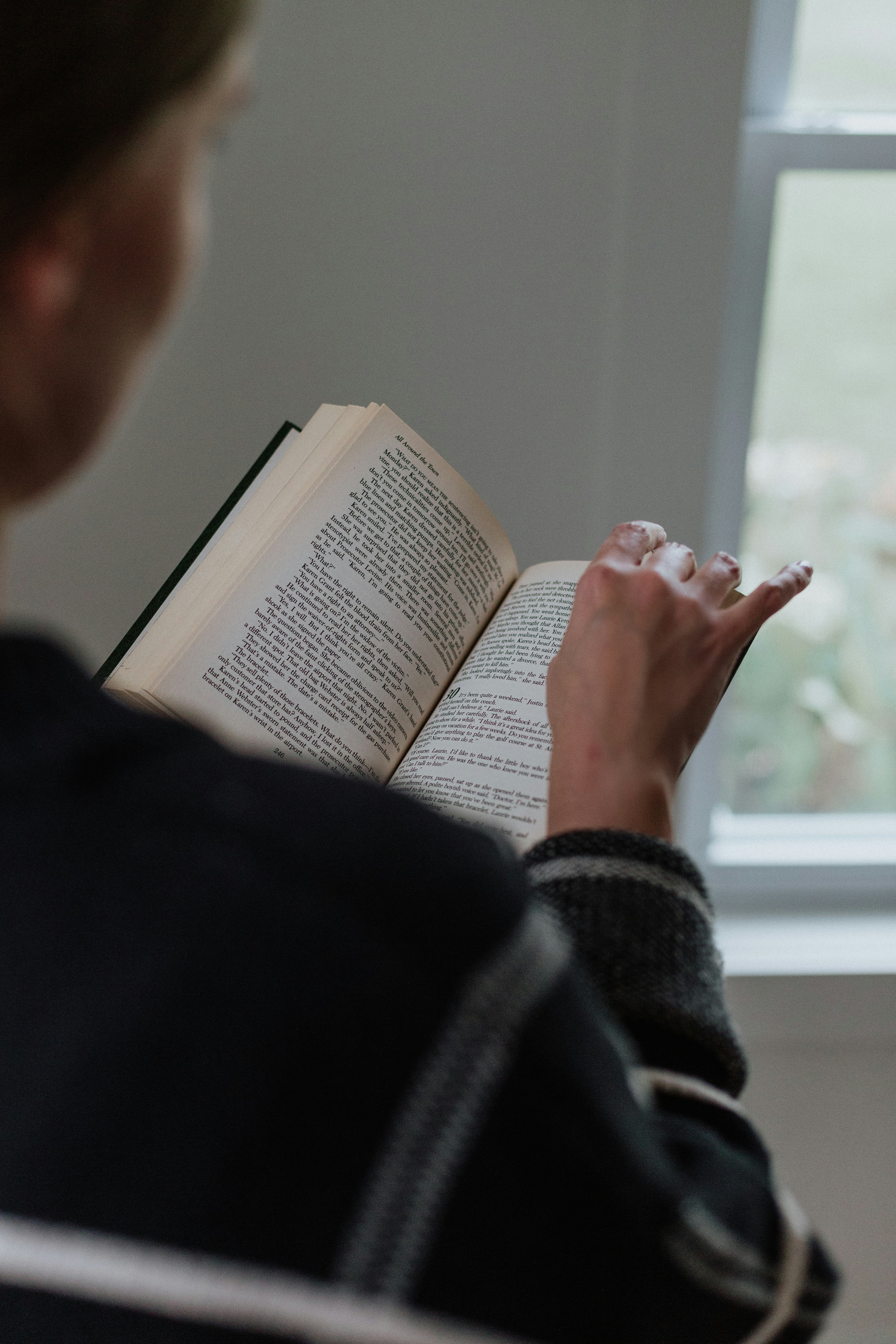 A woman reading a book in front of a window