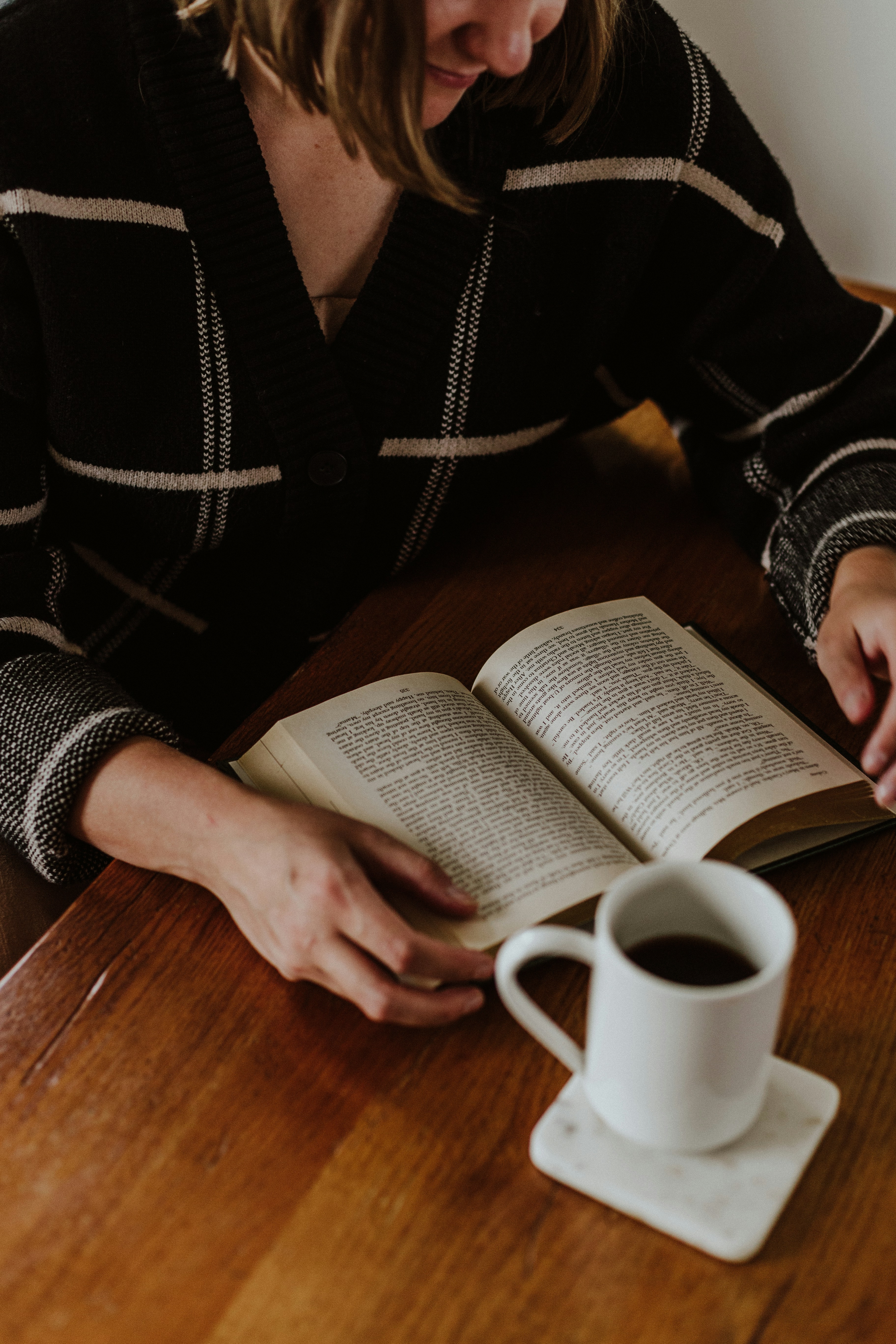 A woman sitting at a table reading a book