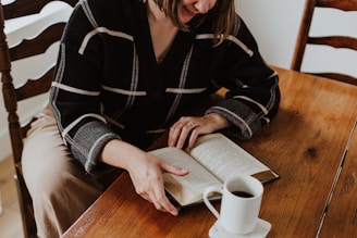 A woman sitting at a table reading a book